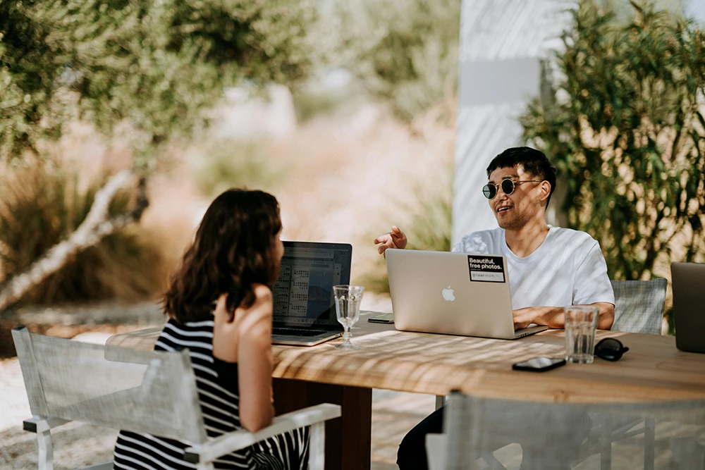 Man and woman discussing work with laptops for Djobzy Hungary remote job and business opportunities.